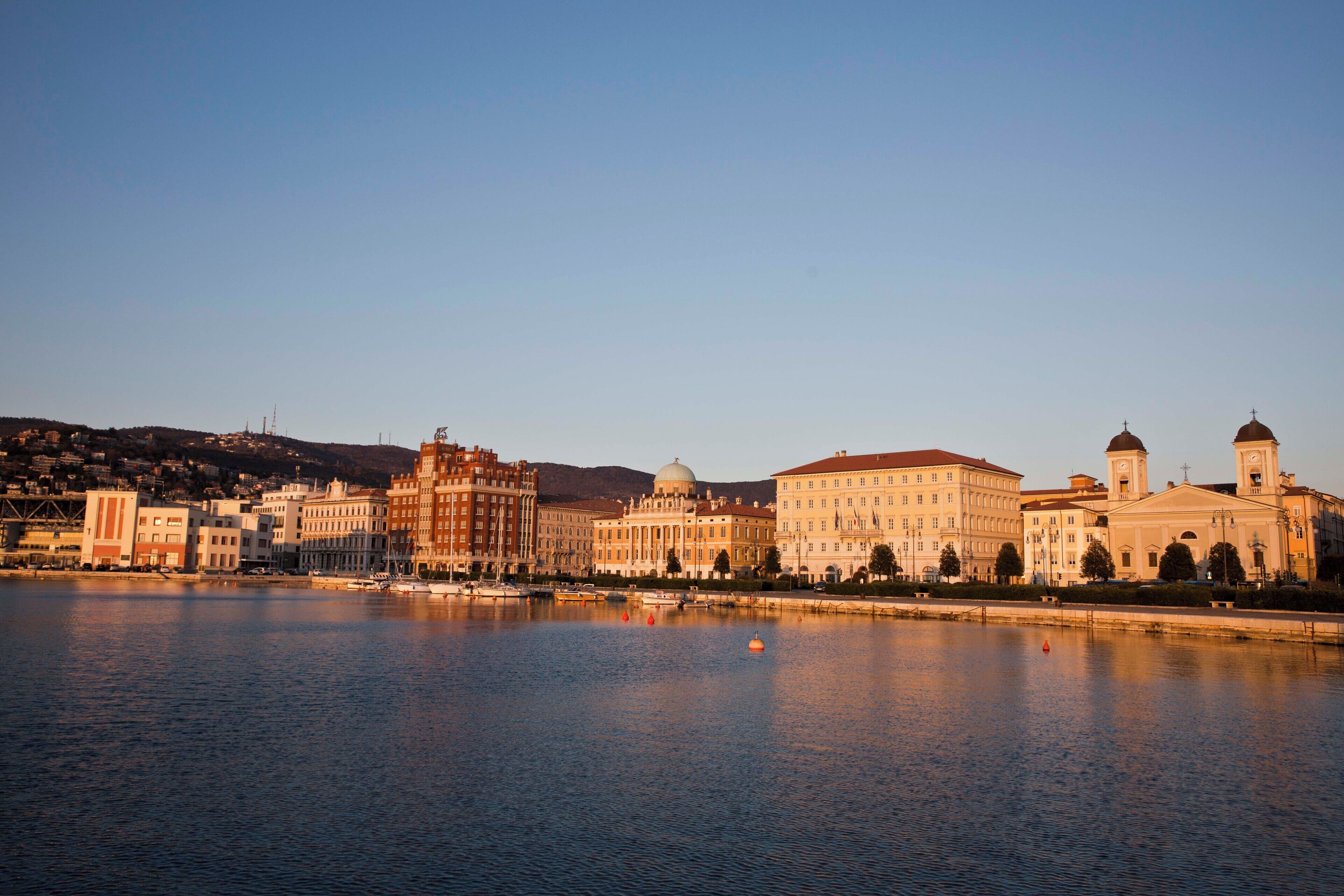 A waterfront cityscape with historic buildings, a river, and a clear sky.
