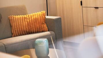 Ein modernes Wohnzimmer mit einem grauen Sofa, einer blauen Vase und einem Holzkabinett.