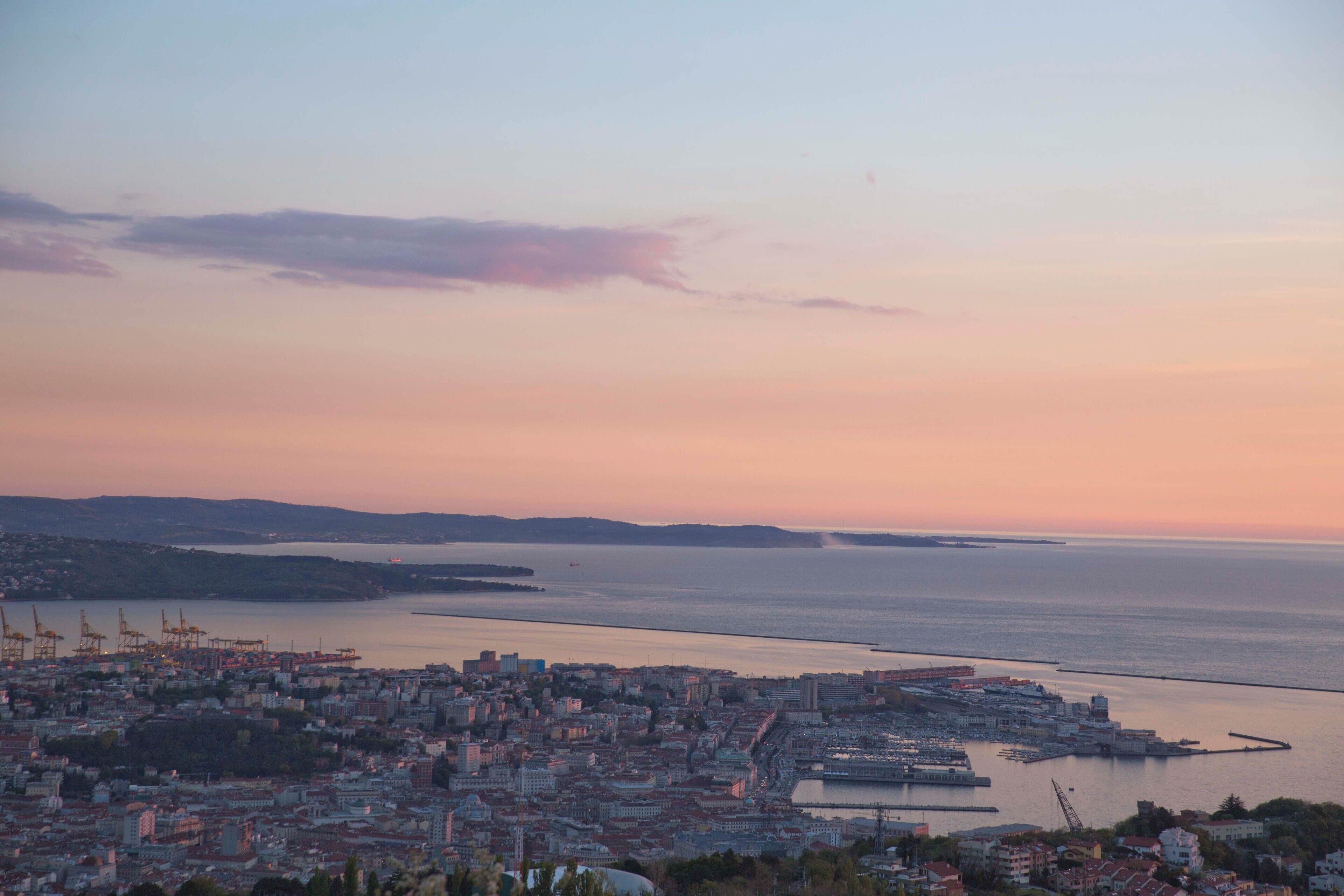 A coastal cityscape with a view of the sea and distant hills.