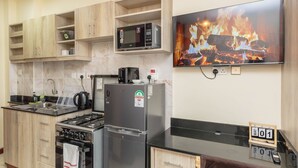 Eine moderne Küche mit Herd, Mikrowelle, Kühlschrank und einem Fernseher, der einen Kamin zeigt.