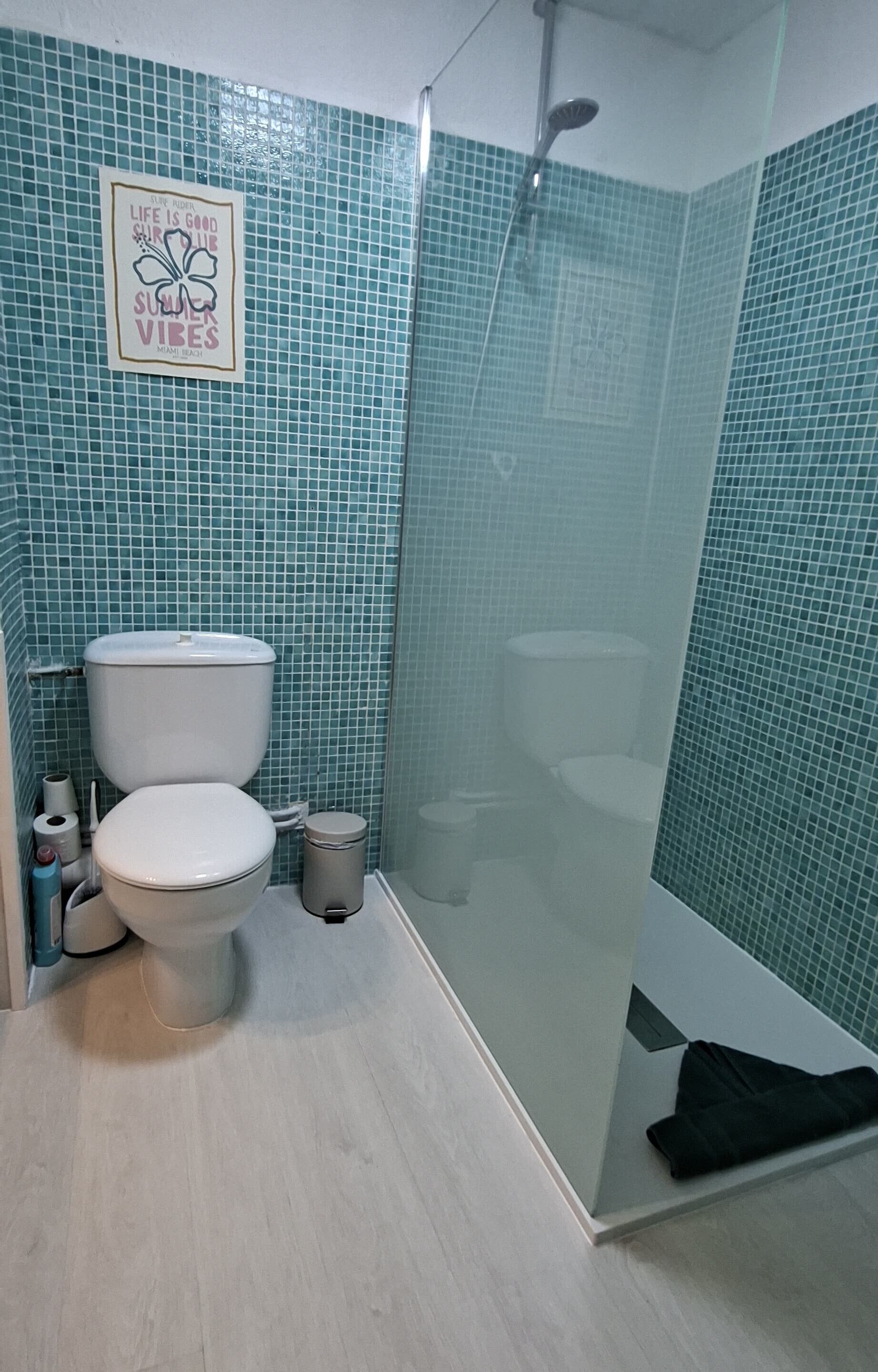 A bathroom with a toilet, a glass shower enclosure, and a wall with a tile pattern.
