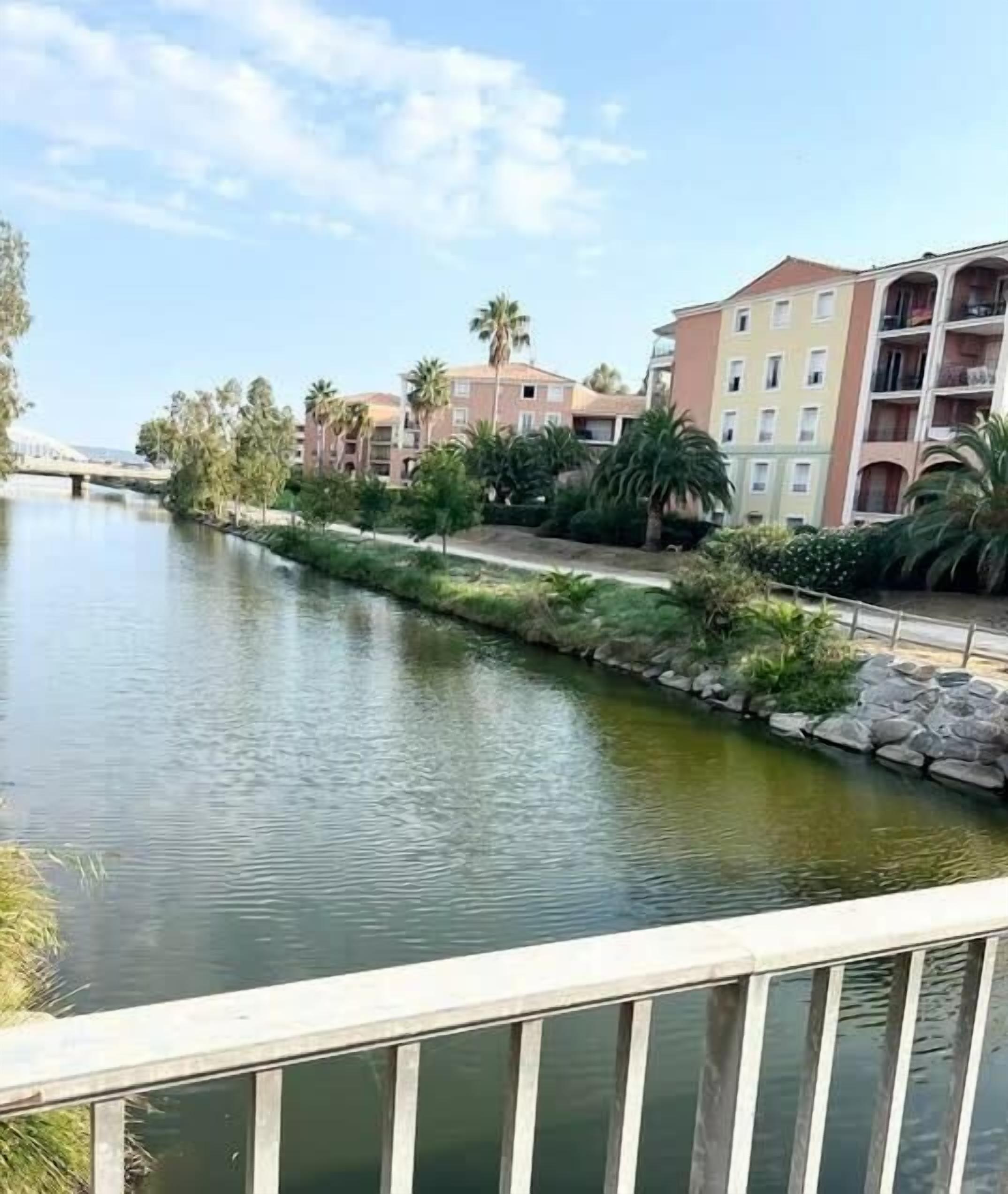 Ein Kanal mit Gebäuden an einer Seite und einer Brücke im Hintergrund.