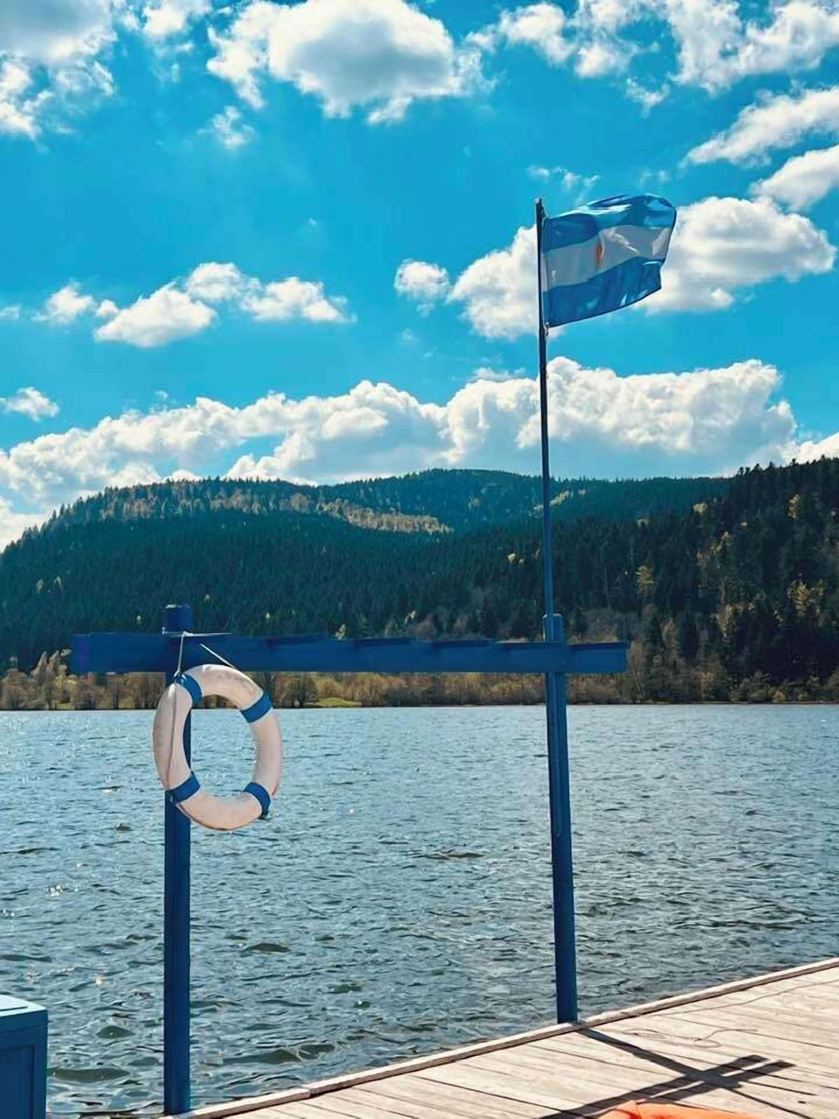 Une jetée en bois, avec une bouée de sauvetage et un drapeau.
