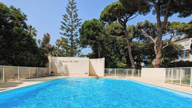 A rectangular swimming pool with clear blue water, surrounded by a white fence and trees. - Apartment of 70 m with shared pool in Hyères (Hyères)