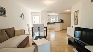 A modern living room with a sofa, a coffee table, a TV, and a dining area with chairs and a table. - Apartment of 70 m with shared pool in Hyères (Hyères)