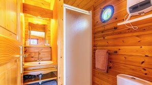 Et badeværelse i en træhytte med vask, spejl og toilet.