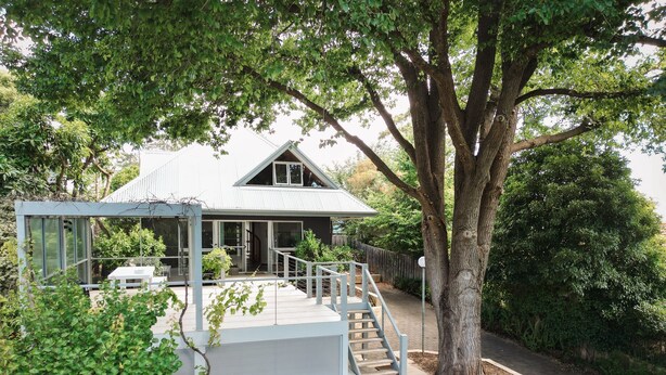 A modern house with a covered patio, a staircase leading to a deck, and a large tree in the foreground. - Terrace Haus Margaret River (Margaret River)