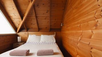 A wooden cabin bedroom with a bed, pillows, and a nightstand.