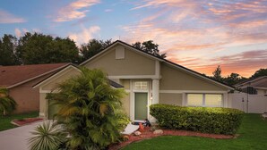 A two-story house with a green front door, a covered porch, and a well-maintained lawn with various plants. - Cozy 3BR Wheelchair Accessible Home with Private Pool Off US 192 Near Disney (Kissimmee)
