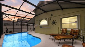 A covered outdoor swimming pool with lounge chairs and a window with blinds. - Cozy 3BR Wheelchair Accessible Home with Private Pool Off US 192 Near Disney (Kissimmee)