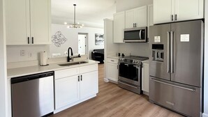 A modern kitchen with white cabinets, stainless steel appliances, and a wooden floor. - Modern Pool Home • Lake view (Kissimmee)