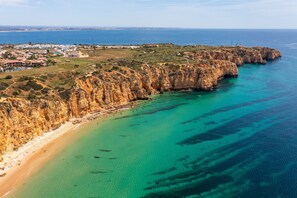 Une zone côtière comprenant une plage, des falaises et une ville située au loin.