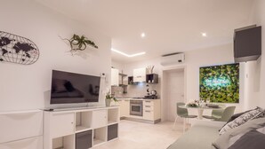Un apartamento moderno con televisión, kitchenette, comedor y cama.