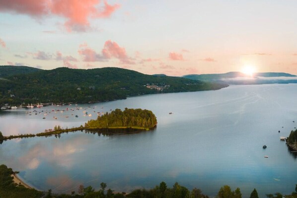 Un lago con una pequeña isla y barcos, rodeado de colinas.