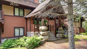 A multi-story building with a thatched roof porch, stone steps, and a stone staircase. - The Nest at Algonquin: Retreat for 2 on Mountain (Mont-Tremblant)