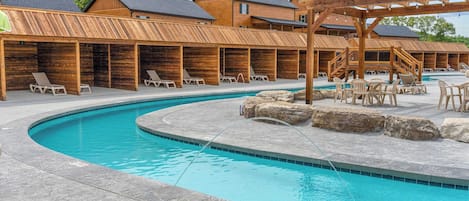 A pool area with lounge chairs, wooden deck, and a wooden pergola.