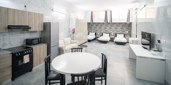 A modern kitchen with a central island, built-in appliances, and a seating area with a round table and chairs. - Studio with Full Kitchen & 3 Beds in Tarxien (Tarxien)