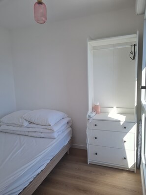 Ein Schlafzimmer mit einem Bett, einem Schminktisch und einer Pendelleuchte.