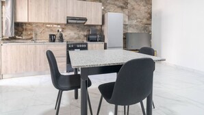 A modern kitchen with a granite countertop, black chairs, and a built-in oven. - Charming 1BR with comfy bed w/WIFI & AC in Tarxien (Tarxien)