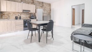 A modern kitchen with wooden cabinets, a marble backsplash, and a dining area with a table and chairs. - Charming 1BR with comfy bed w/WIFI & AC in Tarxien (Tarxien)