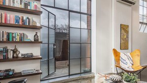 Een moderne woonkamer met een boekenkast, een leren fauteuil, een salontafel en een groot raam.