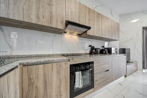 Et moderne køkken med træbeklædt bagvæg, granitbordplade og indbygget ovn.