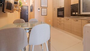 A modern kitchen with a dining area, featuring a glass table, chairs, and a built-in oven.