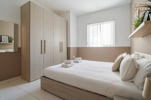 Un dormitorio moderno con una cama grande, un armario y una ventana con persianas.