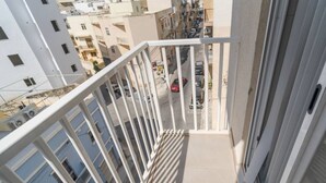A balcony with white railings overlooking a street with cars and buildings. - Cosy 1BR fully equipped Apt with balcony w/WIFI ! (Gżira)