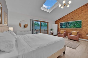 A bedroom with a skylight, a bed, a large window, a view of trees, and a wooden wall. - Lakefront | Sauna | Pool Table | Firepit | Refined (Tobyhanna)