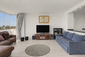 A modern living room with a flat-screen TV, a sofa, a coffee table, and a large window with a view.