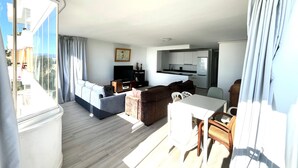 A modern living room with a sofa, a TV, a dining table, and a kitchen area. - Bright 'Luminoso Marbella' Apartment with Sea Views, Wi-Fi and Air Conditioning (Marbella)