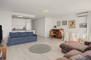 A modern living space with a sofa, a dining table, and a kitchen area.