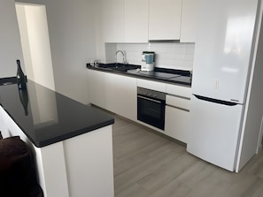 A modern kitchen with white cabinets, a black countertop, and a built-in oven.