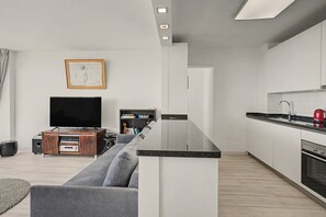 A modern living room with a grey sofa, a flat-screen TV, and a wooden entertainment unit.