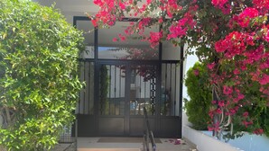 A pathway leading to a building with a gated entrance, surrounded by lush greenery and flowering plants. - Bright 'Luminoso Marbella' Apartment with Sea Views, Wi-Fi and Air Conditioning (Marbella)