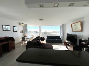 A living room with a sofa, TV, dining table, and chairs.