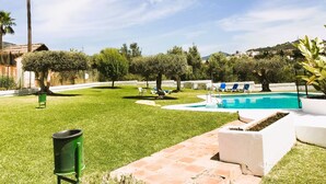A pool area with a clear sky, a palm tree, and a well-maintained lawn. - Bright 'Luminoso Marbella' Apartment with Sea Views, Wi-Fi and Air Conditioning (Marbella)