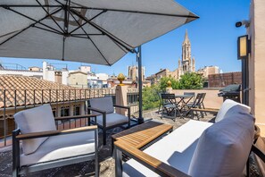 An outdoor patio with seating, a table, and an umbrella. - Spectacular rooftop with cathedral views and BBQ (Palma)