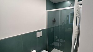 Un baño moderno con bidé, inodoro y cabina de ducha de vidrio.