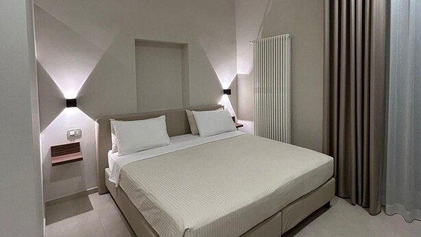 Un dormitorio moderno con una cama grande, mesitas de noche, una lámpara de pared y un radiador.
