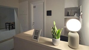 Un mostrador de recepción con un código QR, una planta en maceta y una lámpara de escritorio.