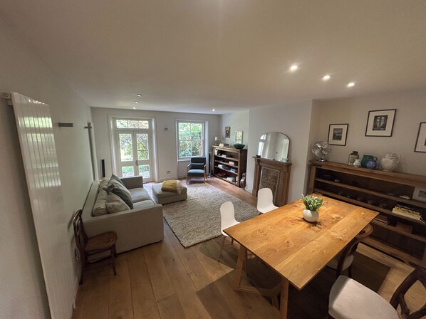 A spacious living area with a sofa, a dining table, and a bookshelf.