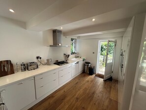 A modern kitchen with white cabinetry, a gas stove, and a window overlooking a garden.