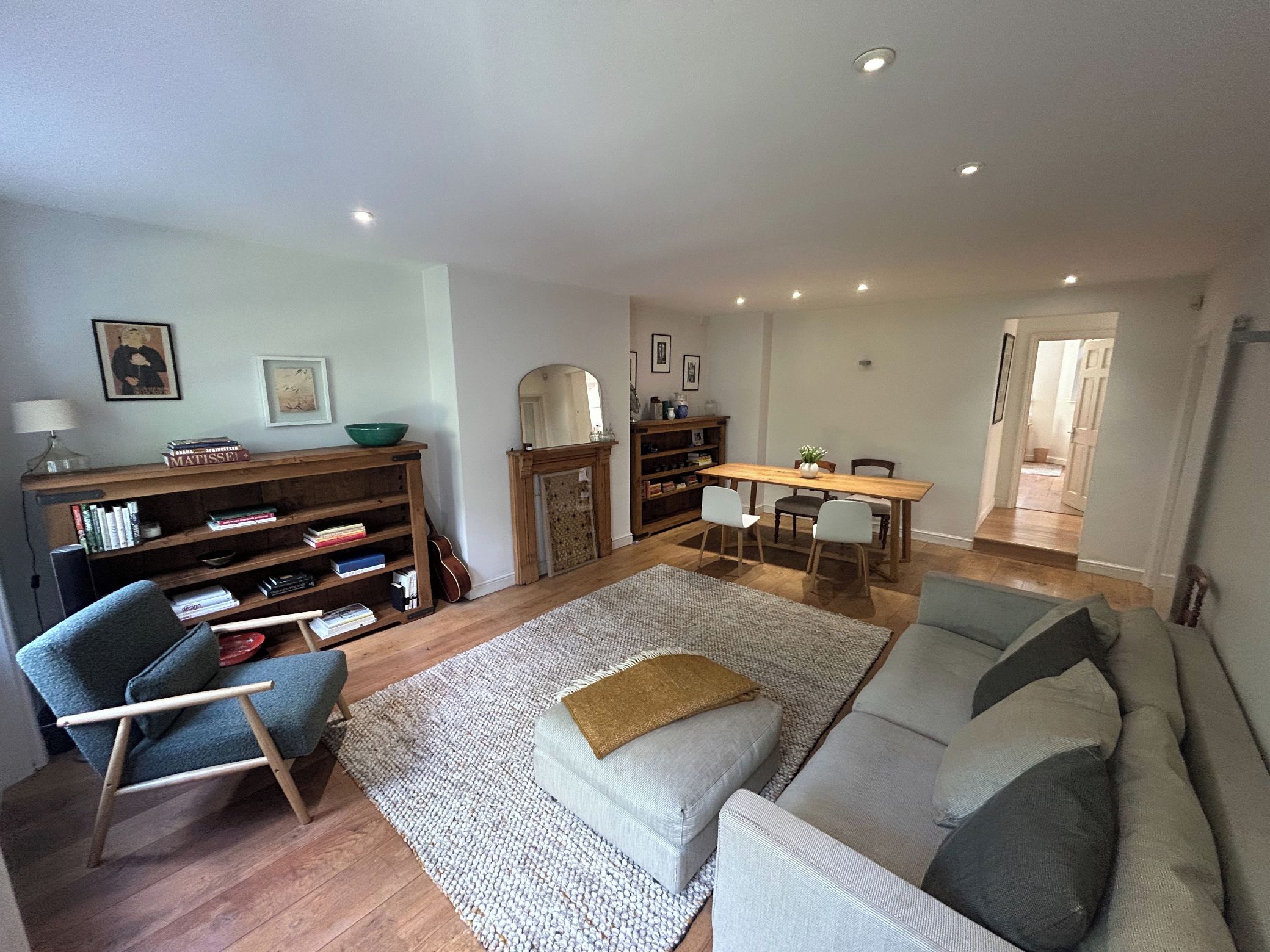 A living room with a sofa, a chair, a coffee table, a bookshelf, and a dining table.
