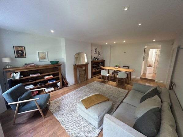 A living room with a sofa, a chair, a coffee table, a bookshelf, and a dining table.