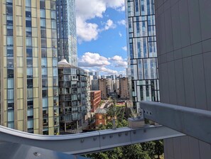 A high-rise building with a modern glass facade, a pedestrian walkway, and a view of the cityscape.