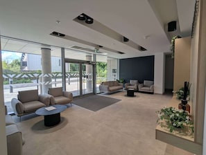 A modern lobby with seating, a reception desk, and large windows.