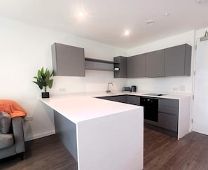 A modern kitchen with grey cabinets, a white countertop, and a built-in dishwasher.