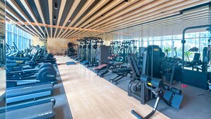 A modern gym with various exercise equipment, wooden ceiling beams, and large windows. - Urban Escape Studio Pool, Gym & Stylish Living (Dubai)